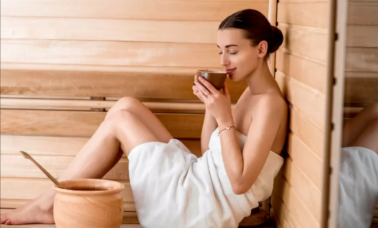 Eine Frau trinkt Tee in der Sauna