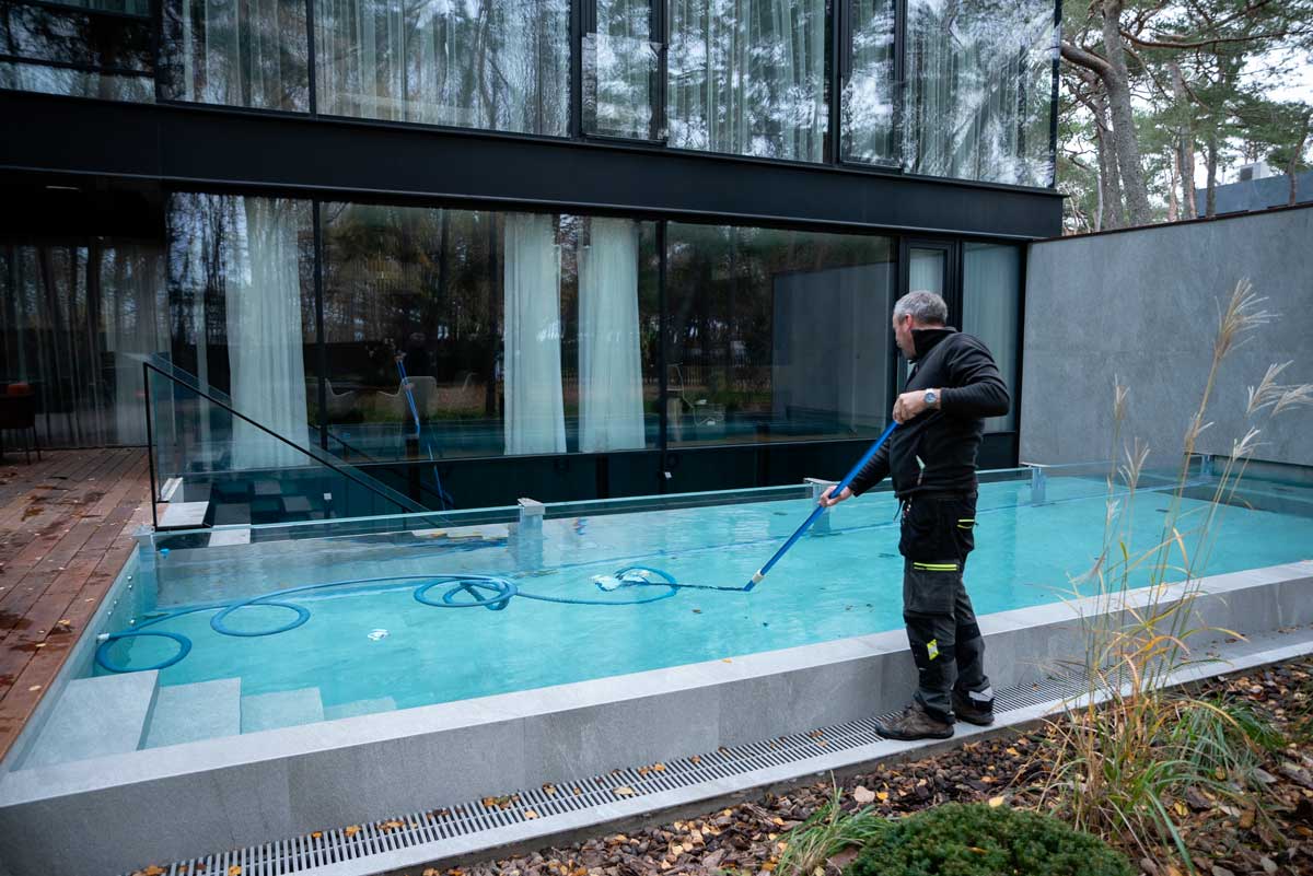 Freibad mit trübem und schmutzigem Wasser, braune Flecken und Schmutz auf der Oberfläche, eine Person steht neben dem Becken