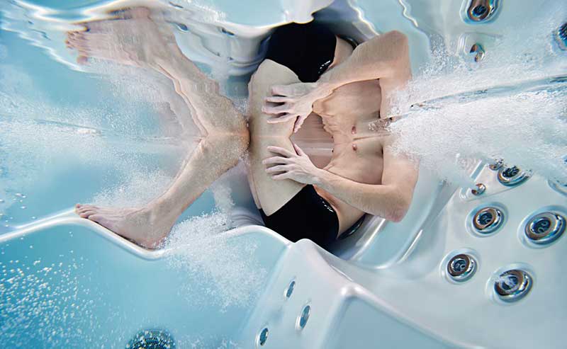 Frau entspannt sich in einer ergonomischen Liege eines USSPA-Whirlpools mit in Betrieb befindlichen Hydromassagedüsen.