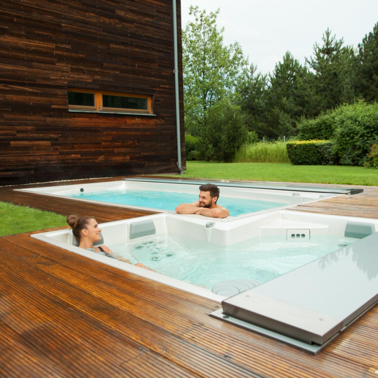 Ein Paar entspannt sich in den auf einer Holzterrasse installierten USSPA-Außenpools und Swim-Spa-Pools.