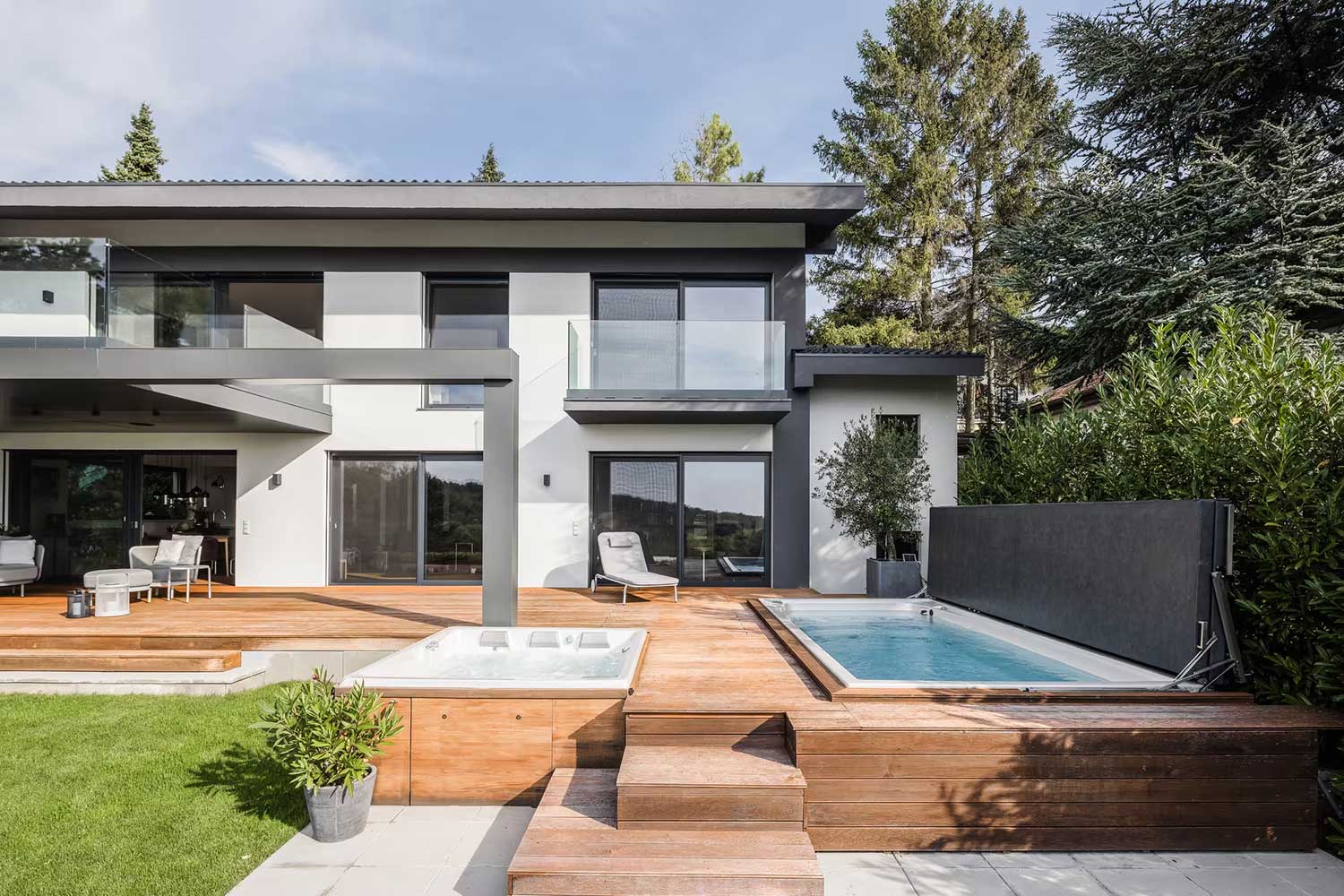 USSPA-Spa- und Schwimm-Spa-Pools mit erhöhten Abdeckungen wurden neben der Terrasse eines modernen Hauses installiert.