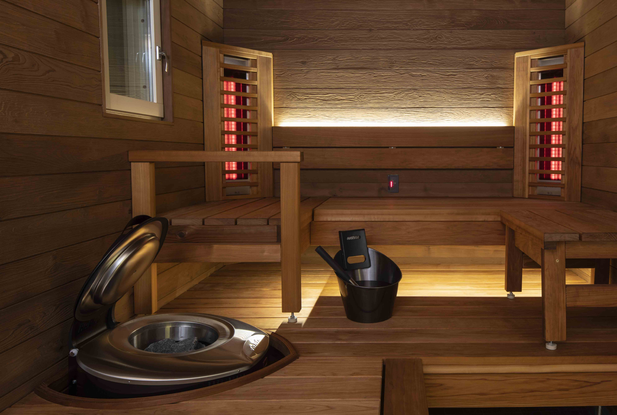 Infrarotsauna-Interieur mit Holzbänken, Heizelementen und einem Ofen zur Entspannung und für Wohlbefinden